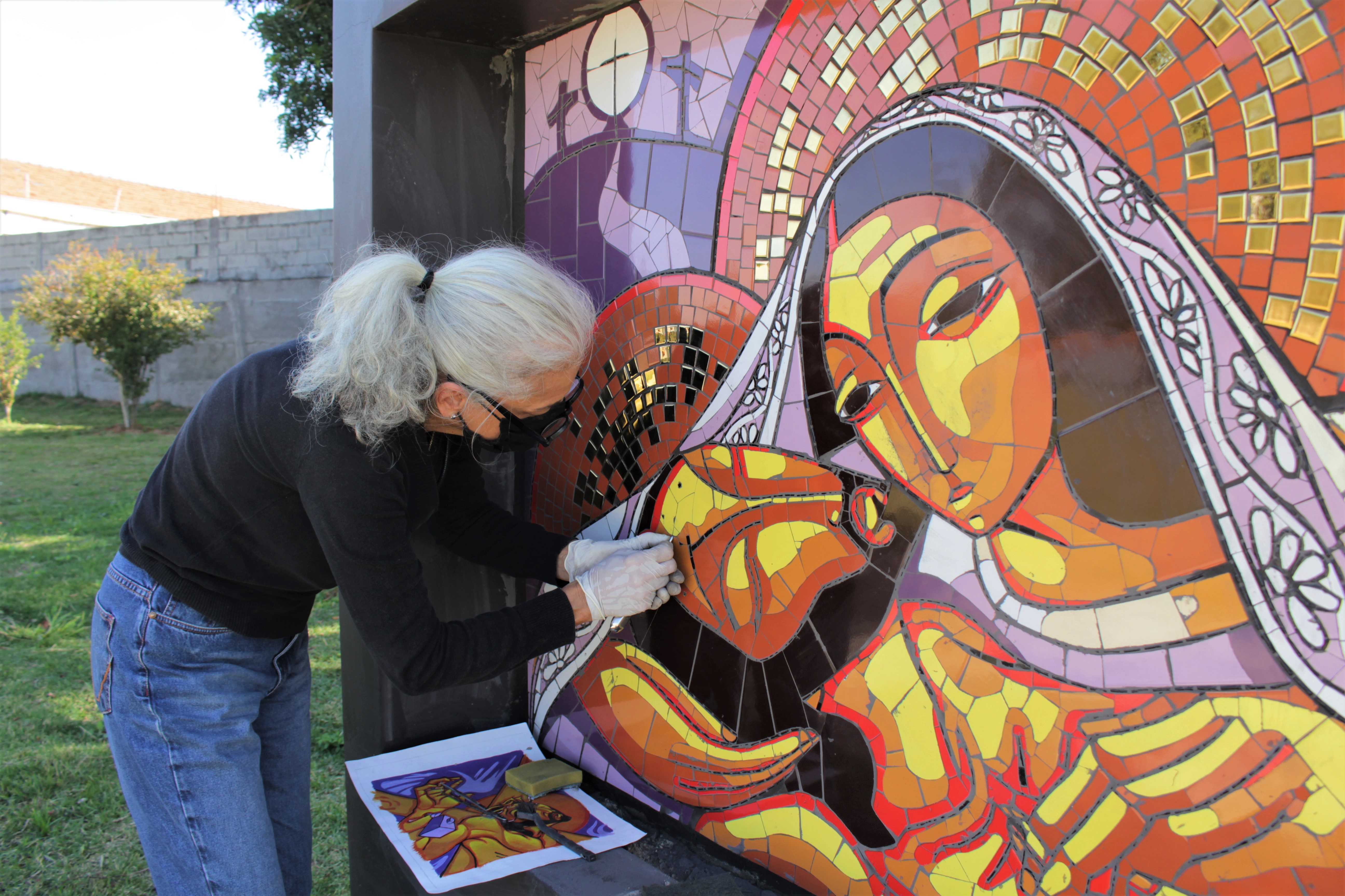 A arquiteta Regina Steurer, do Ateliê-escola de Mosaico do Projeto Âncora, afirma que cada peça dos painéis leva cerca de três minutos para ser confeccionada. Foto - Vitória Mendes